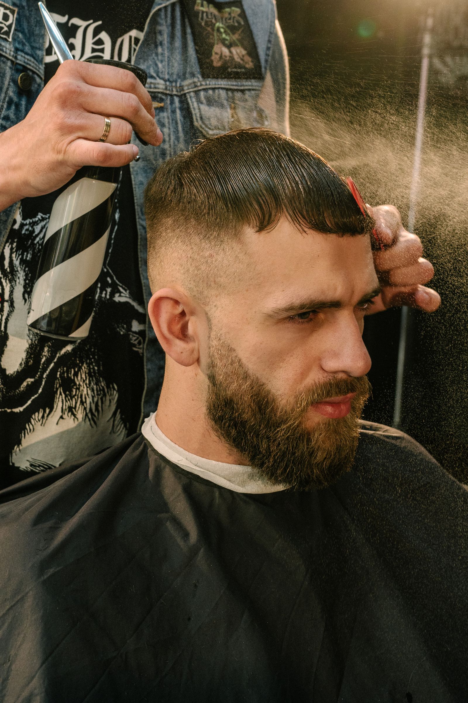 Man met baard en een French crop met korte pony bij de kapper