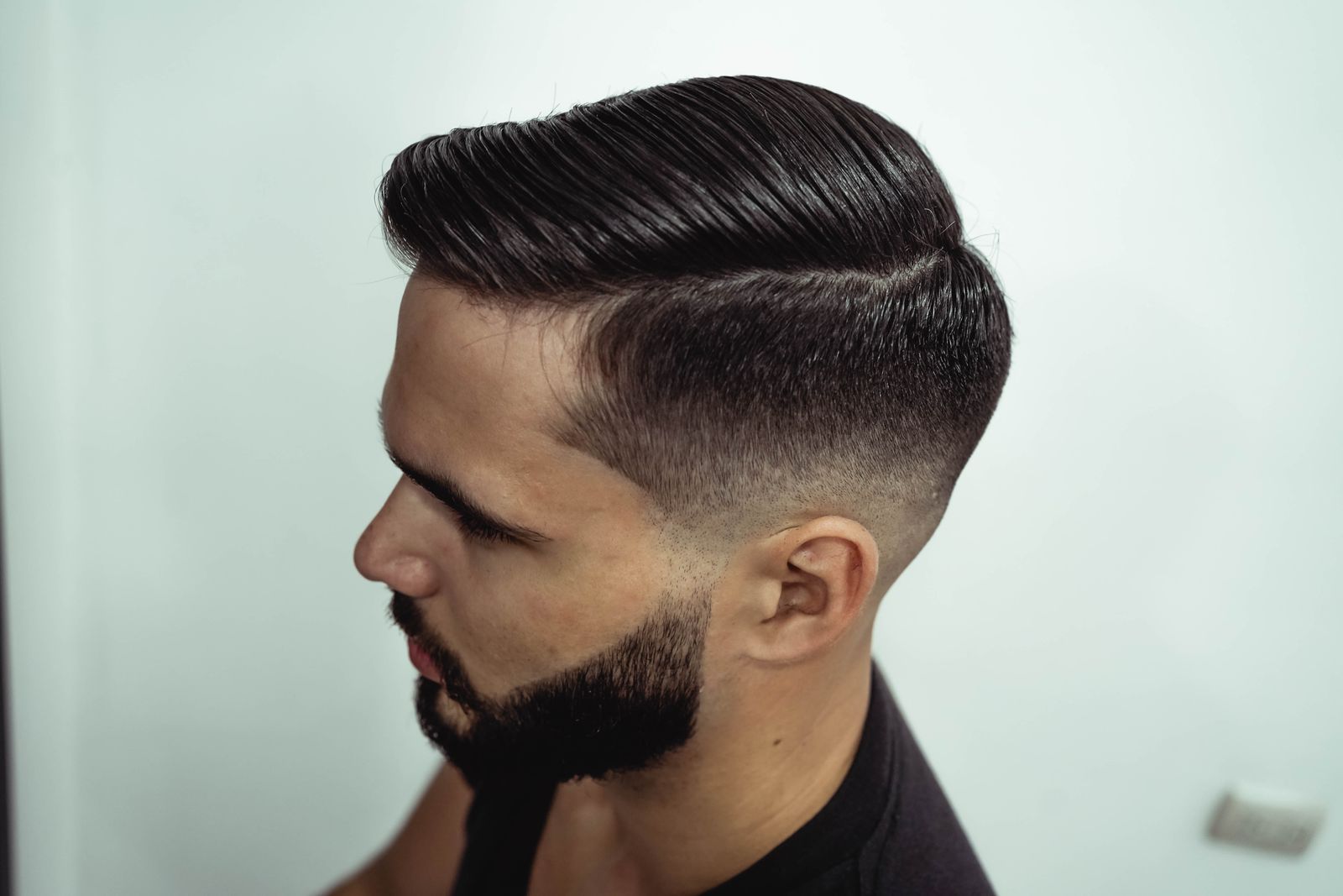Man met een strakke zijscheiding, naar opzij gekamd haar en een fade
