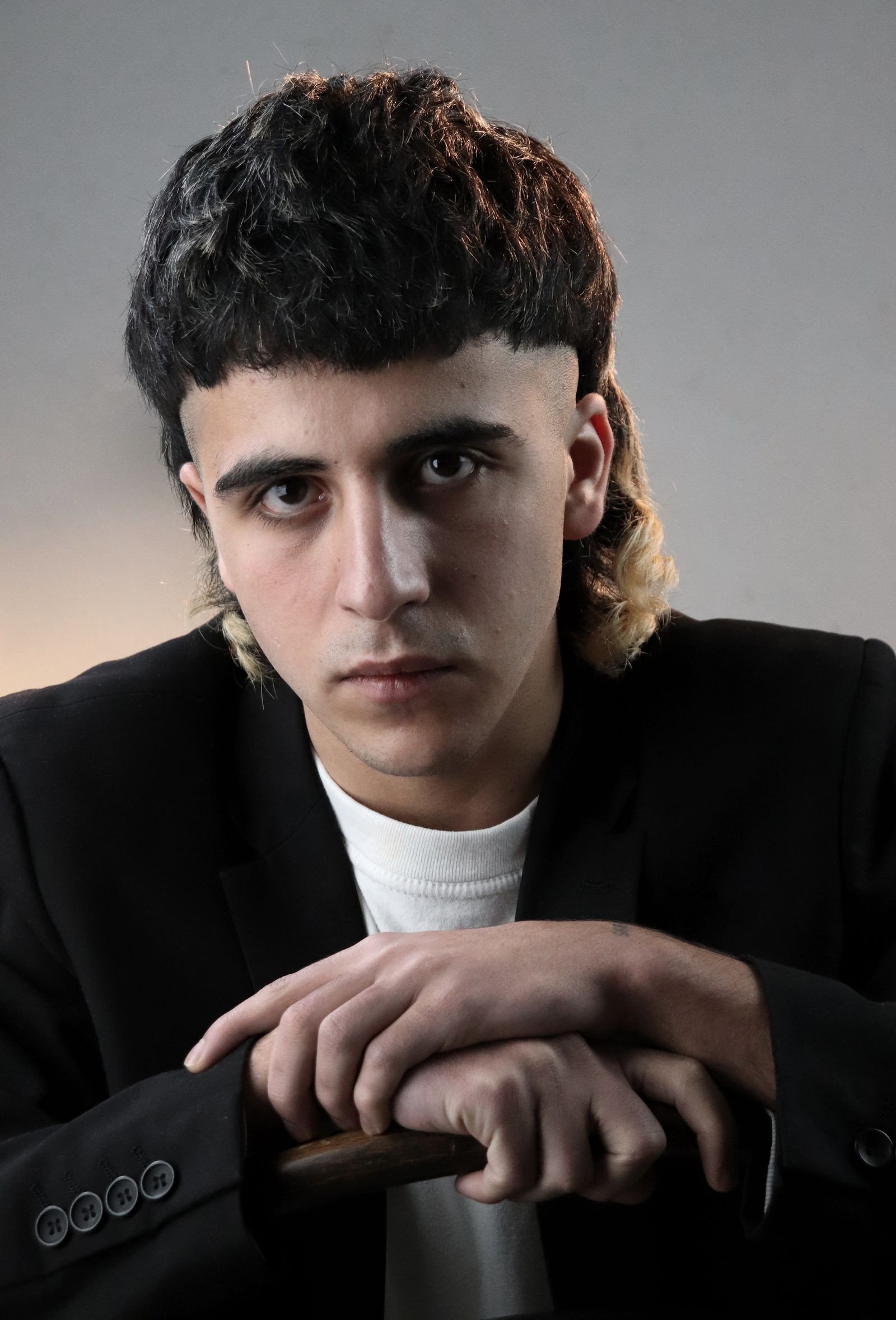 Jonge man met een moderne mullet, kort aan de voorkant en lang in de nek