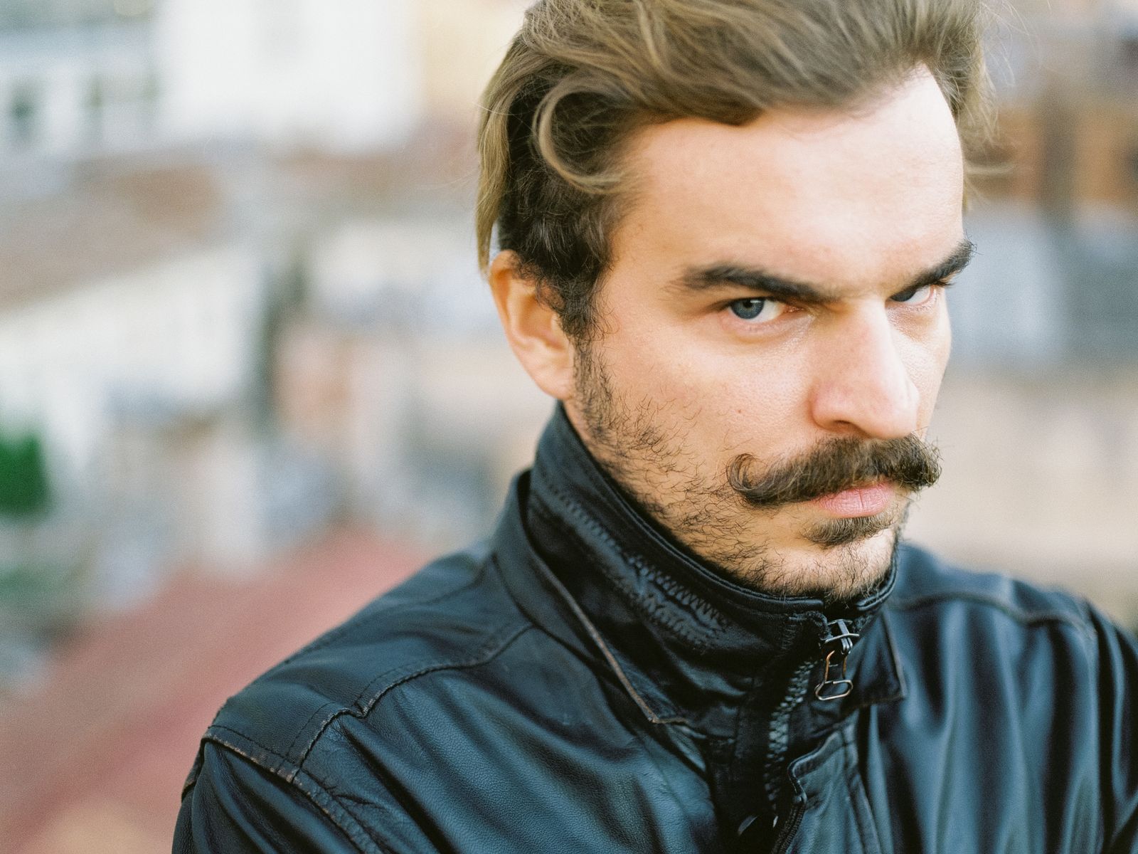 Man met een volle chevronsnor die de bovenlip bedekt, in een donker leren jack
