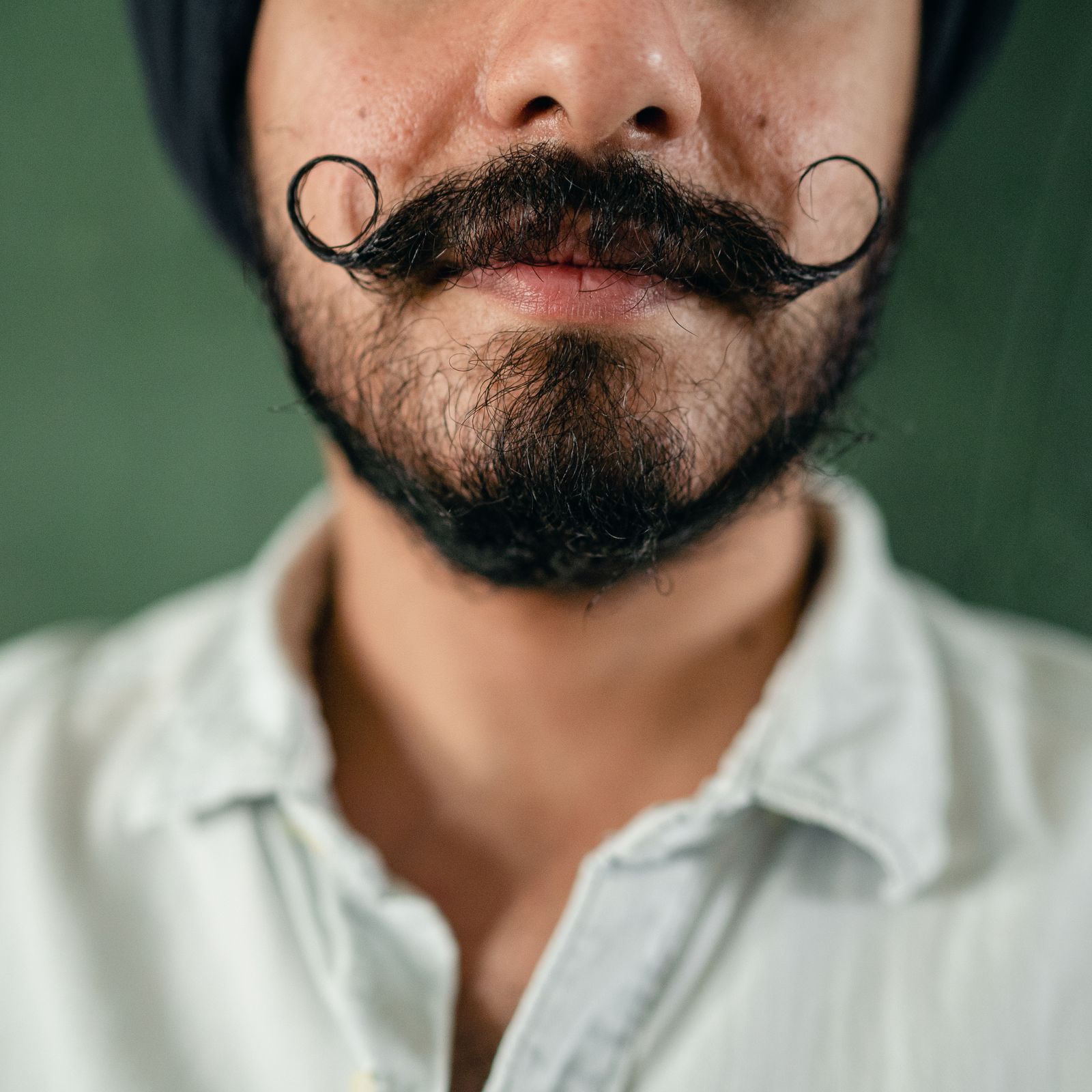 Close-up van een man met een handlebar-snor met opgekrulde uiteinden en een korte baard