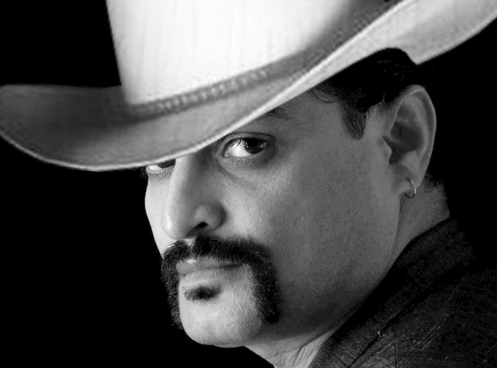 Zwart-witportret van een man met een cowboyhoed en een horseshoe-snor die langs zijn mondhoeken naar beneden loopt