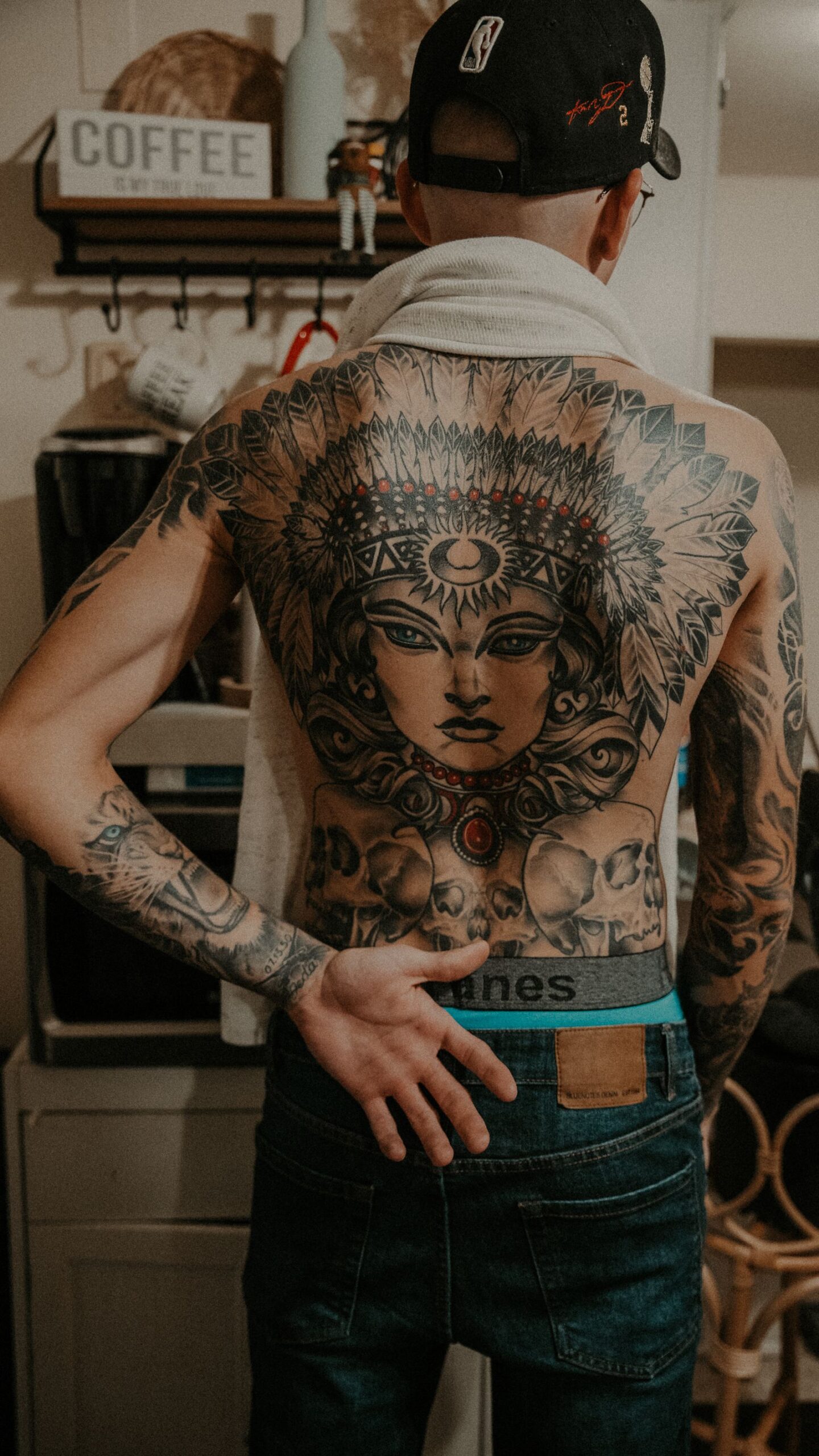 Man van achteren met een groot getatoeëerd portret dat zijn hele rug bedekt