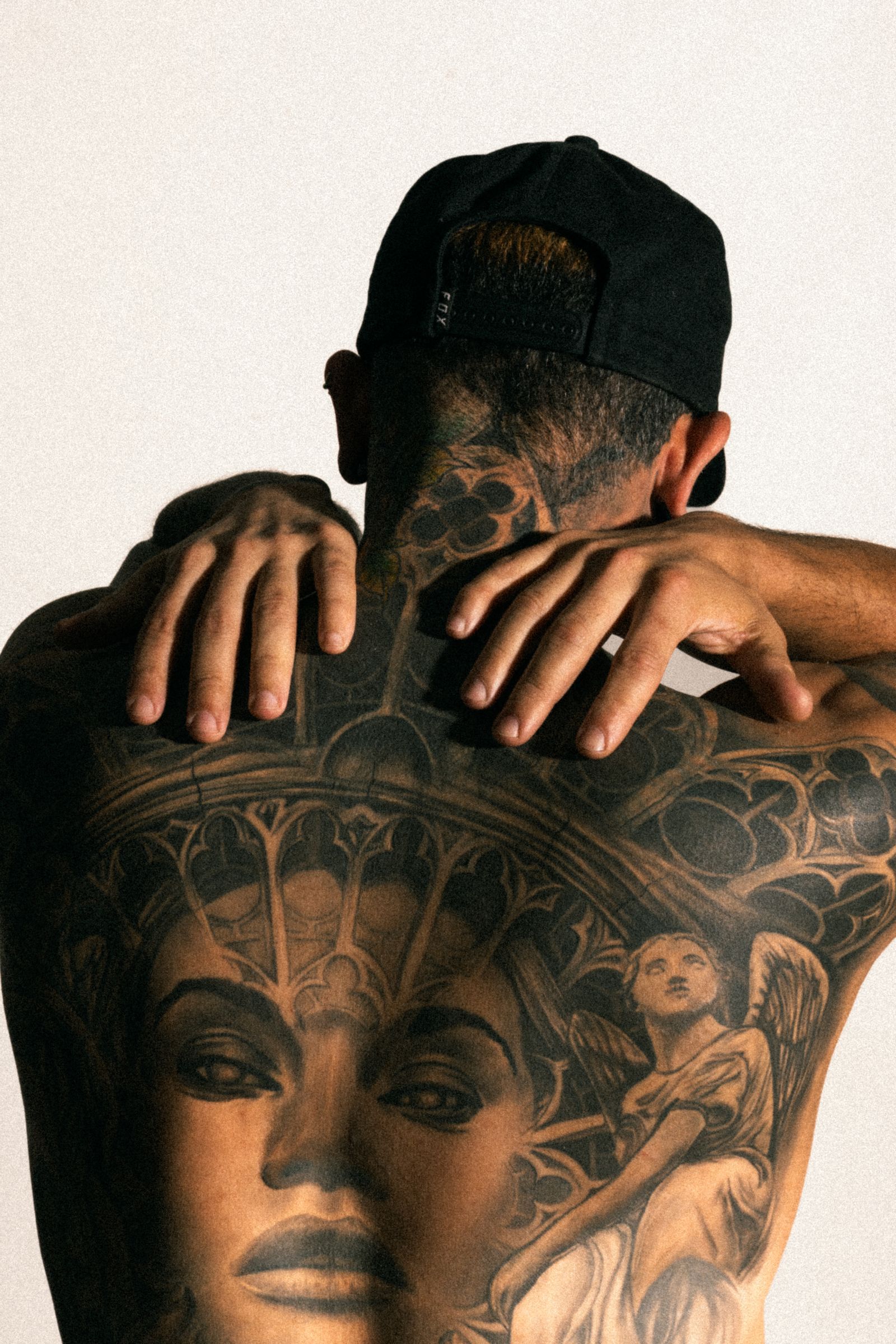 Rug van een man met een realistisch getatoeëerd vrouwenportret in grijstinten onder een gotische boog