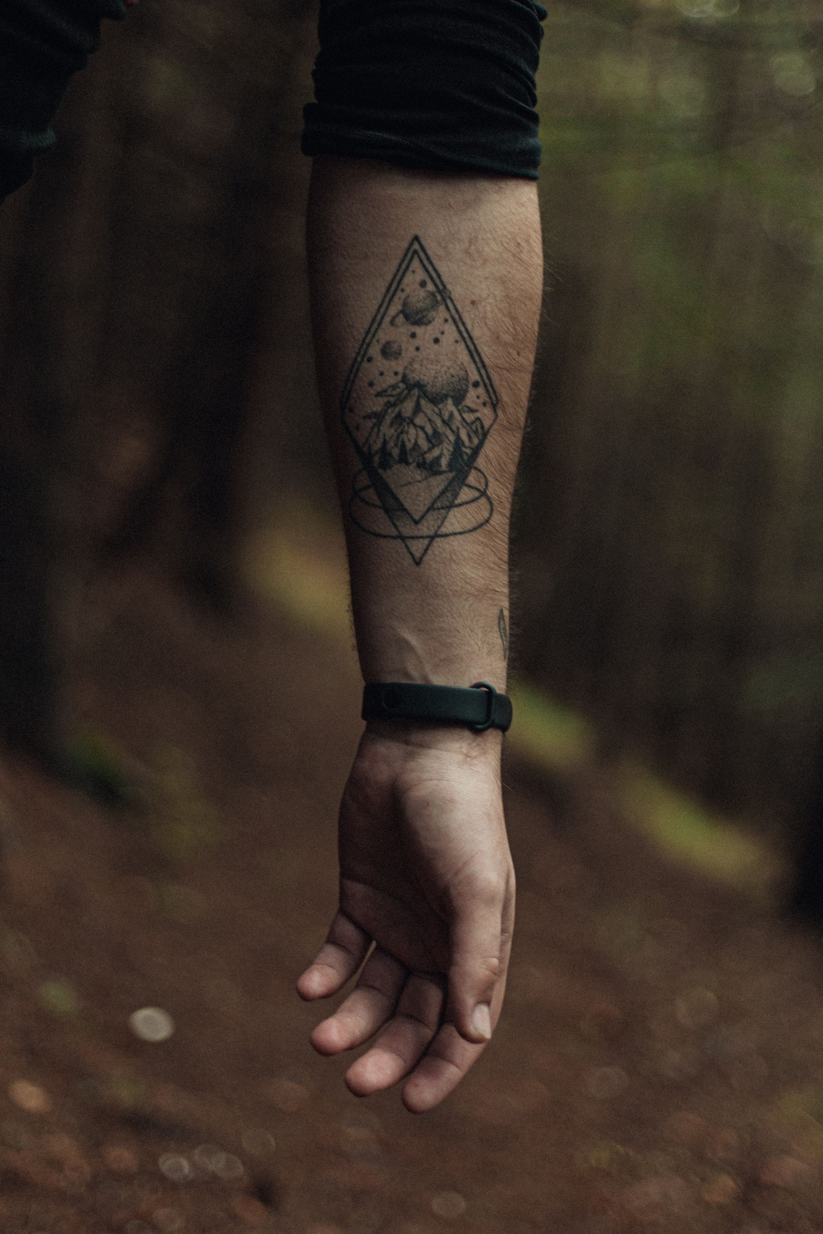 Onderarm van een man met een geometrische tattoo van een ruit met daarin bergen
