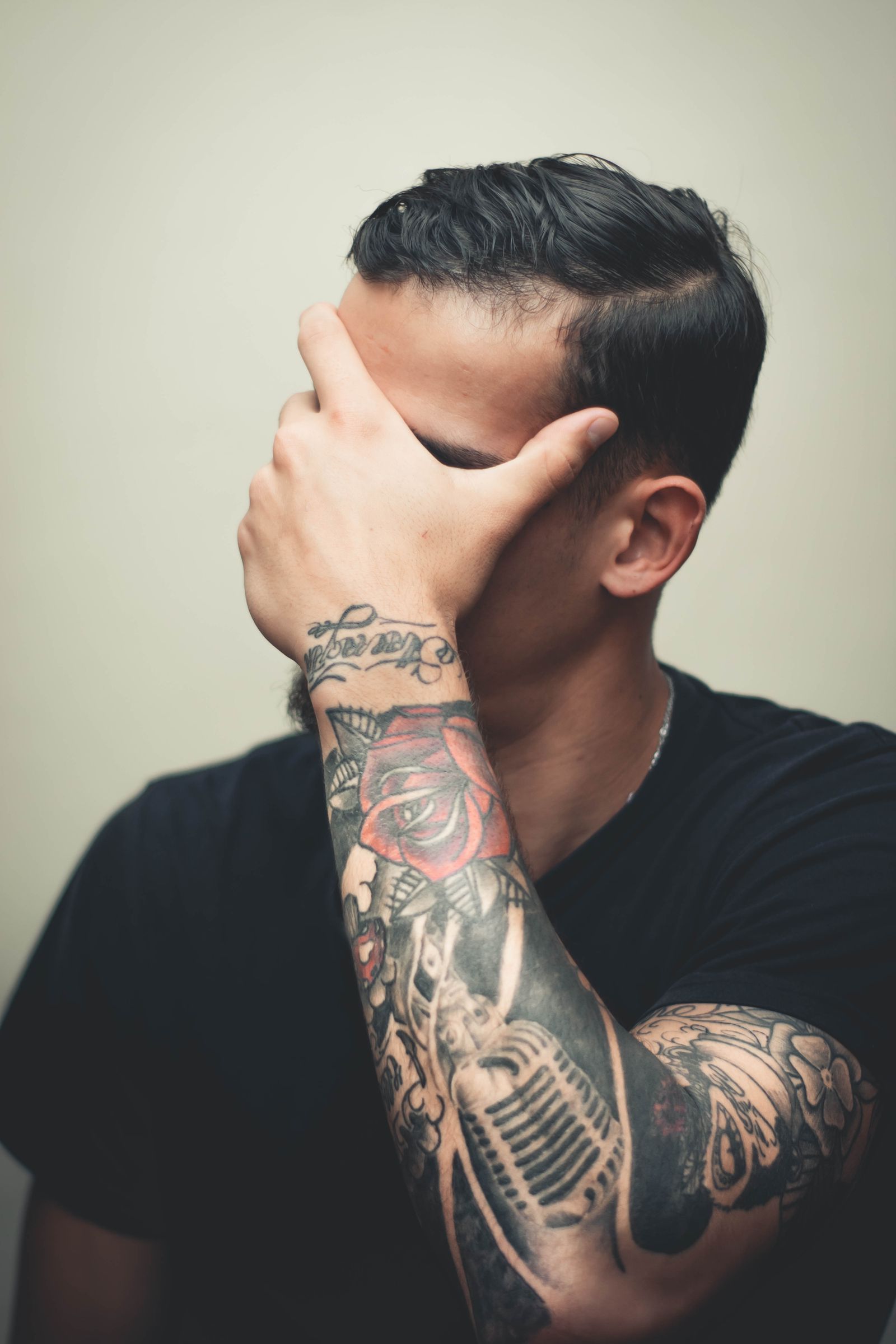 Man in een zwart T-shirt met een volledige sleeve tattoo van schouder tot pols